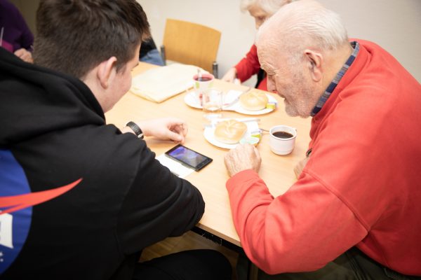 Junger LIesinger hilft Pensionisten mit dem Smartphone