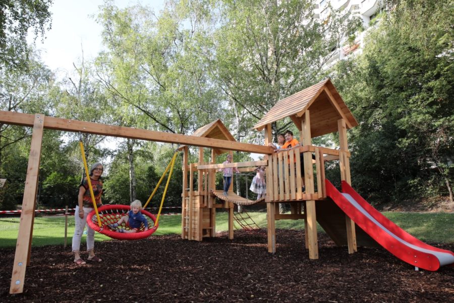 Kinderspielgerät mit Kinder, Erwachsene steht bei Schaukel