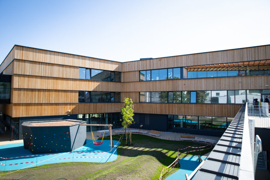 Außenfassade der neuen Schule mit Spielgeräten