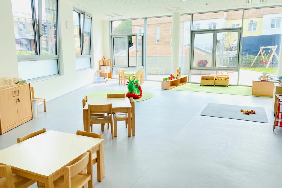 Kindergartengruppenraum Blickrichtung Fenster, im Vordergrund 2 Tische mit Sesseln rundherum