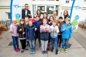 Gruppe von Kindern mit 4 Erwachsenen vor dem Eingang einer Volksschule