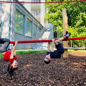 2 Kids hängen mit dem Kopf nach unten auf einem Seil
