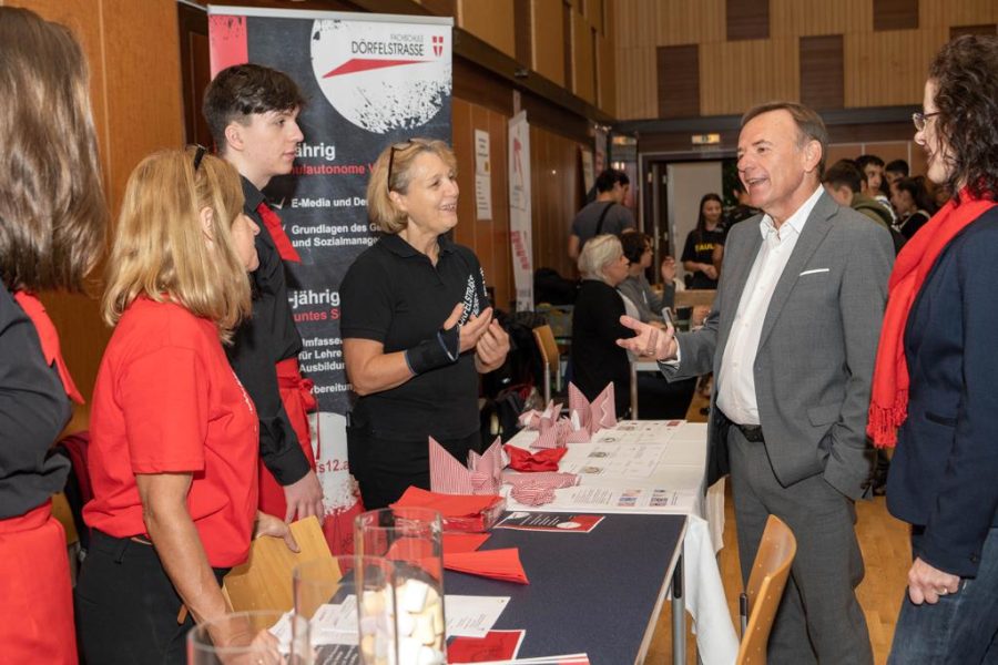Gerald Bischof steht mit 3 Personen an einem Infotstand und ist im Gespräch