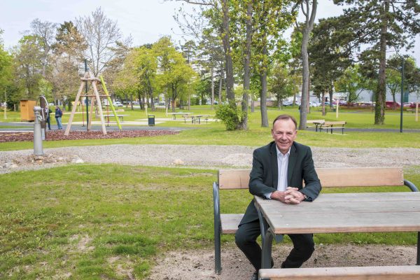 Gerald Bischof sitzt an einem Tisch, im Hintergrund der neue Park