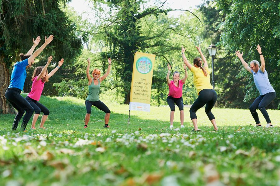 mehrere Sportlerinnen und Sportler beim Turnen im Grünen